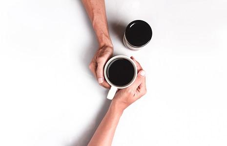 Two people holding a mug of coffee