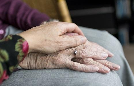 A person holding the hand of an elderly person