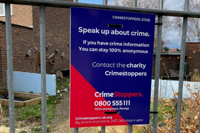 A sign for Crimestoppers on a fence.