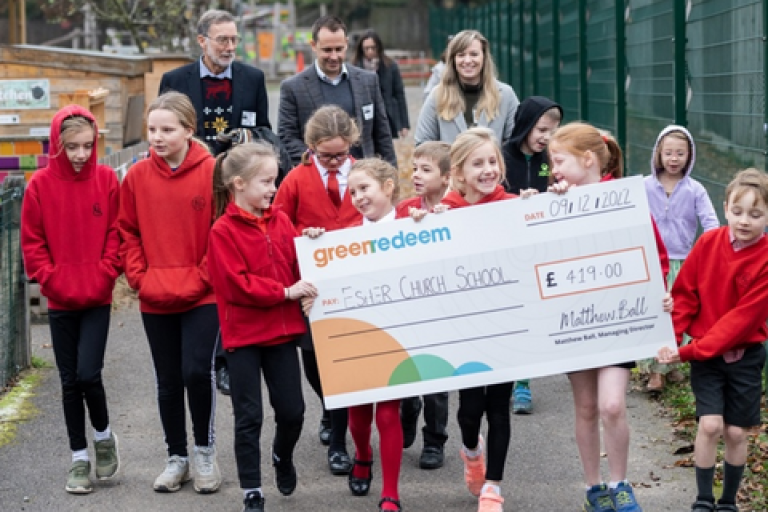 Pupils at Esher Church School carrying a large cheque from Green Redeem after winning a recycling competition.