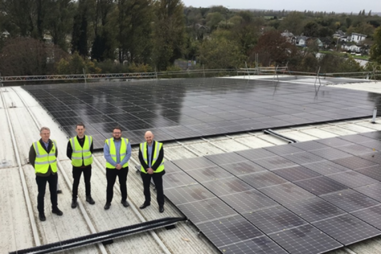 Team from Elmbridge Borough Council wearing high-vis jackets and standing in front of newly installed solar panels.