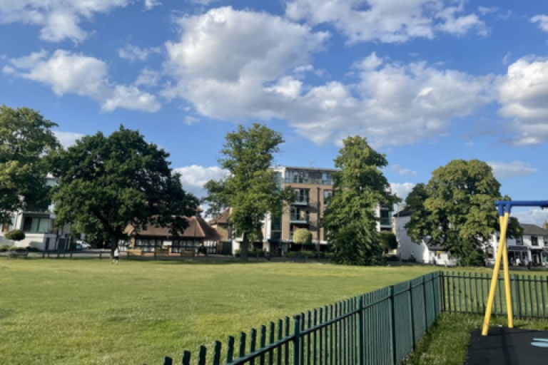 A green space in Hersham surrounded by a playground and residential buildings.