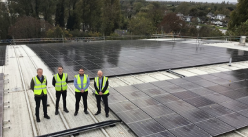 Team from Elmbridge Borough Council wearing high-vis jackets and standing in front of newly installed solar panels.