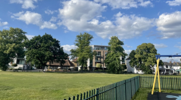 A green space in Hersham surrounded by a playground and residential buildings.