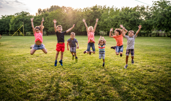 Children jumping up in a green grassy field