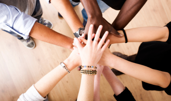 Hands reaching into the centre demonstrating teamwork