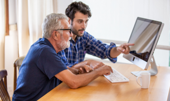 Older man being shown information on computer screen