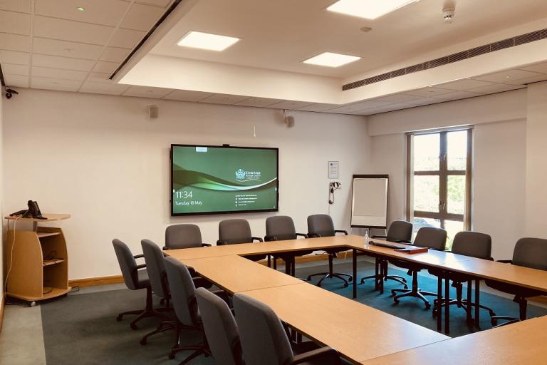 Meeting room with tables, chairs, screen and flipchart