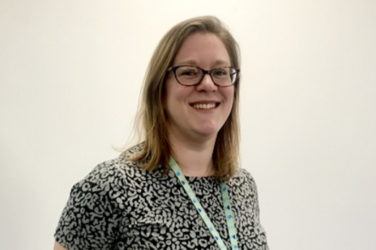 Jenny Margetts smiling and standing in front of a white wall