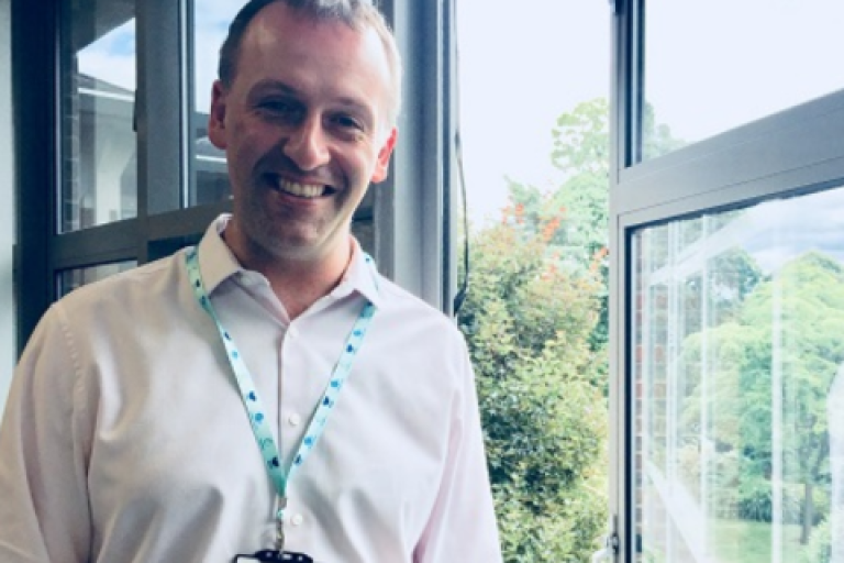 Paul Falconer smiling in front of a window