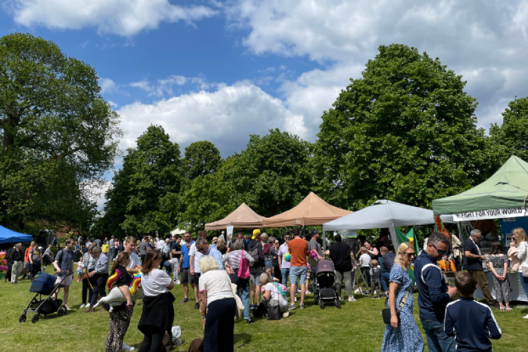 People attending a summer fair with market stalls
