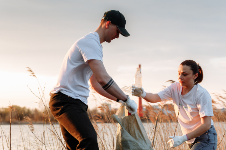 An image showing 2 people picking litter in a rural area.