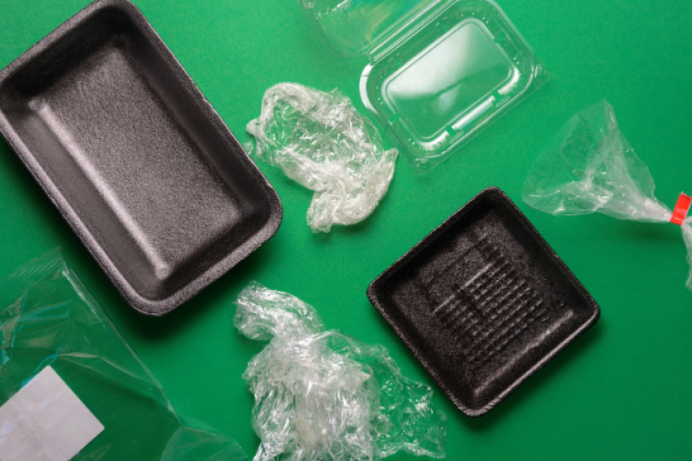 An image of different types of plastic packaging on a green background.