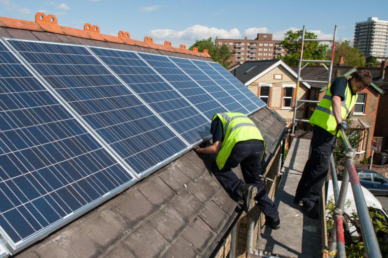 Two men on a roof installing solar panels