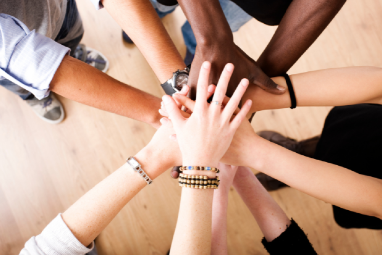 Hands reaching into the centre demonstrating teamwork