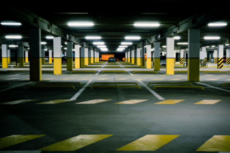 Underground car park with a black car in the centre parked.