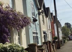 A street of terraced houses, each house painted a different pastel colour