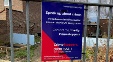 A sign for Crimestoppers on a fence.