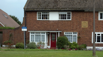 End of terrace house with a red door.