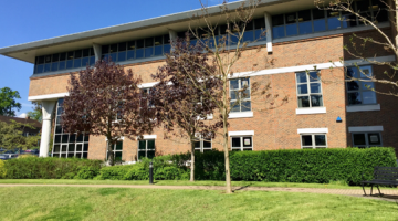 Exterior of the Elmbridge civic centre behind trees.