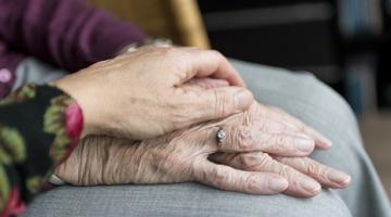 A person holding the hand of an elderly person