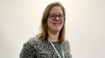 Jenny Margetts smiling and standing in front of a white wall