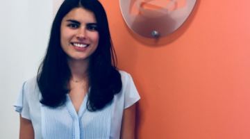 Katie George smiling in front of an orange wall