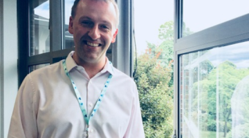 Paul Falconer smiling in front of a window