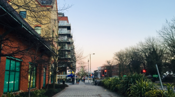 A pathway in Walton-on-Thames lined with flats and next to a nearby road in the evening