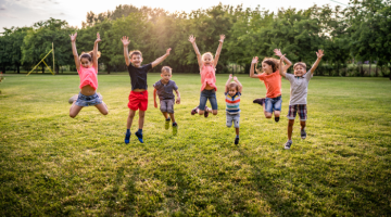 Children jumping up in a green grassy field