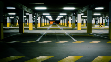 Underground car park with a black car in the centre parked.