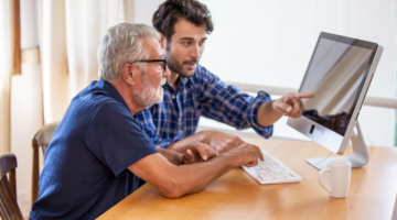 Older man being shown information on computer screen